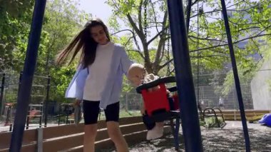 Kız canlı bir parkta salıncakta sallanıyor, güneş ışığı yaprakların arasından süzülüyor, açık havada neşe ve eğlence ortamı yaratıyor.