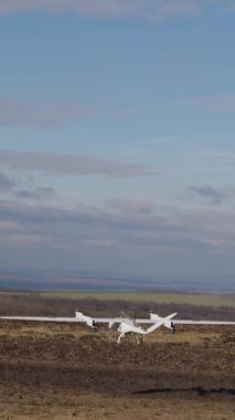 Beyaz İHA açık alanların üzerinden yüksek irtifada havalanıyor. Drone uzun mesafelerde tarım arazilerini filme alır. Şehrin dışındaki tarım arazileri, açık hava, açık gökyüzü. Teknoloji ve tarım alanlarındaki yenilikler.