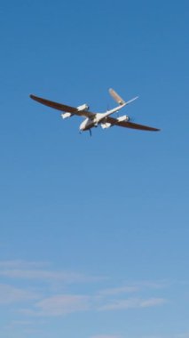 Uçak şeklinde beyaz akıllı dron uçar ve açık mavi gökyüzünde film çeker. Devlet güvenliği için en son model insansız hava aracı taramaları. Yenilikçi teknoloji kavramı