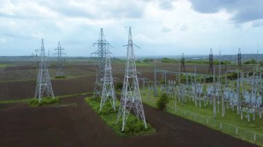 Kırsal bir alanda elektrik hatları ve iletim kulelerinin hava perspektifi, enerji dağıtımında teknoloji ve doğa arasındaki bağlantıyı vurguluyor