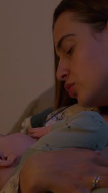 Huzurlu genç anne, geceleri kucağında bebek beşiği taşıyor. Pijamalı sevgi dolu kadın, akşam yatak odasında oturan küçük çocuğu sakinleştirir.