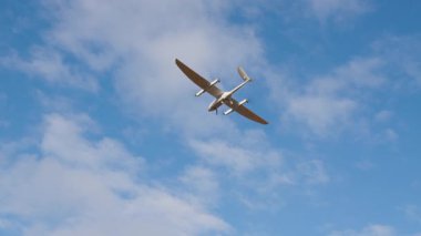 Parlak mavi gökyüzünde süzülen hava aracı modern tasarımı ve özelliklerini vurgulayarak teknoloji ve fotoğrafçılıktaki gelişmeleri sembolize ediyor.