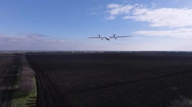 Hava aracı büyük siyah bir alanın üzerinde uçuyor, tarımda son teknolojiyi gösteriyor, tarım operasyonlarında verimliliği ve hassasiyeti artırıyor.
