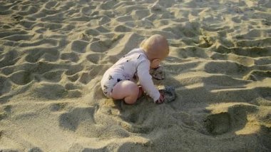 Bebekler kumlu plajda oynak aktiviteler yapar. Sıcak güneş ışığı ve yumuşak kumla çevrili dokuyu kazar ve keşfederler. Masumiyet ve keşif gösterirler.