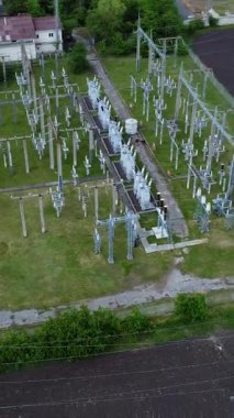 Elektrik hatları ve iletim kulelerinin yer aldığı, yeşil alanlar ve altyapı ile çevrili bir elektrik ağının hava perspektifi, enerji dağıtım sistemlerini gösteriyor