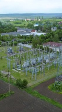 Enerji hatları ve kulelerin bulunduğu, yeşillik ve alanlarla çevrili bir elektrik santralinin hava perspektifi, enerji altyapısının karmaşıklığını vurguluyor.