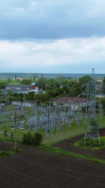 Elektrik hatları ve metro istasyonları, yemyeşil alanlara ve bulutlu gökyüzüne karşı kurulmuş, elektriğin günlük hayattaki kritik rolünü vurguluyor.