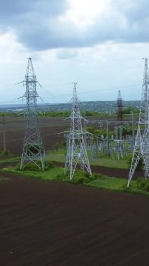 Açık alanlar ve dramatik bulutlarla çevrili, elektrik hatları ve iletim kuleleri, günlük faaliyetler için elektrik altyapısına olan bağımlılığı gözler önüne seriyor.