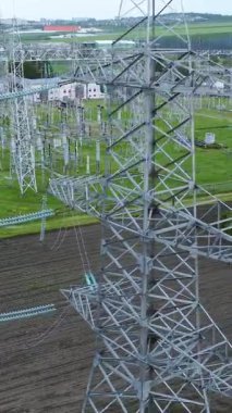 Yüksek voltajlı elektrik hatları ve iletim kuleleri, elektrik altyapısının ölçeği ve önemini vurgulayan yeşil bir alanda belirgin bir şekilde gösteriliyor.