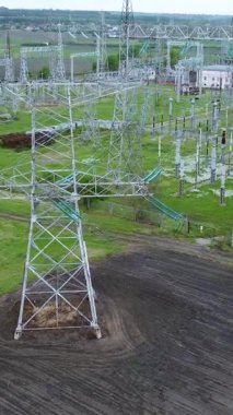 Yüksek voltajlı iletim kuleleri ve elektrik hatları, ulusal elektrik şebekeleri ve enerji dağıtımının temel altyapısını gösteren geniş yeşil araziye hakim durumda