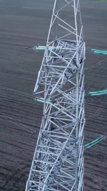 Yüksek elektrik iletim kulesi geniş tarım arazisinin üzerine yükseliyor, enerji altyapısı ve kırsal manzaranın karışımını vurguluyor, güç dağılımının önemini vurguluyor