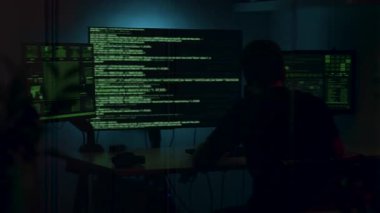 Karanlık bir odada, yeşil metinlerle aydınlatılmış, yüksek teknolojili bir konsantrasyon ve dijital keşif atmosferi yaratan, birden fazla ekranda veri analizi yapan kişi.