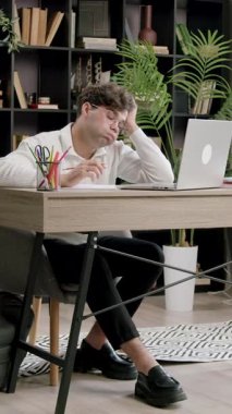 Yorgun adam elinde dinleniyor ve masadaki görevi düşünerek dizüstü bilgisayara bakıyor. Sandalyenin yanında açık sırt çantasıyla bacak bacak bacak üstüne attım.