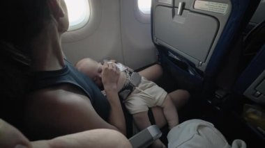 Anne, uçuş sırasında huzur içinde uyuyan bebeğini kollarında tutar ve huzurlu bir uçak ortamında aralarındaki bağın sıcaklığını ve samimiyetini yakalar.