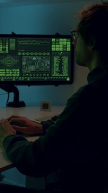 Karanlık bir odadaki birden fazla ekranda veri analizi yapan kişi, canlı dijital görüntüler ve kodlama etkinlikleriyle dolu teknolojiden anlayan bir ortamı vurguluyor.