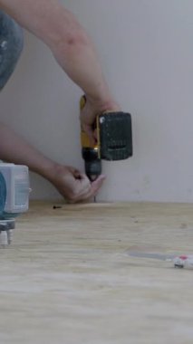 Erkek inşaat işçisi zeminde diz çökerek, malzemeleri yapıştırmak için matkap kullanıyor, alet ve çalışma alanı ile duvarcılık ve sıva becerilerini gösteriyor, Chisinau, Moldova Cumhuriyeti - 17 Temmuz 2025