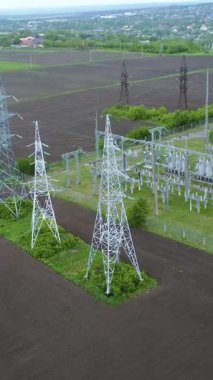 Yüksek voltajlı iletim kuleleri ve santralleri, yeşil alanlarla çevrili kırsal bir alanda enerji dağılımı ve bağlantılılığını gösteren bir ulusal elektrik ağı oluşturur.