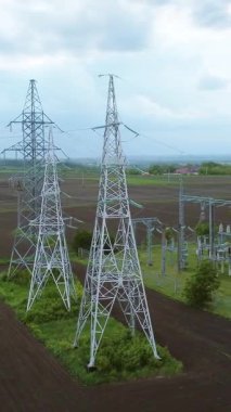 Kırsal bir alanda elektrik hatları ve iletim kulelerinin hava perspektifi, enerji dağıtımında teknoloji ve doğa arasındaki bağlantıyı vurguluyor