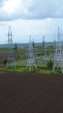 Yüksek elektrik iletim kuleleri bulutlu bir gökyüzünün altında geniş bir alana yerleştirilmiş ve enerji taşımacılığı ve dağıtımı için gerekli altyapıyı göstermektedir.