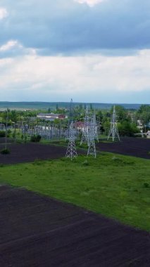 Geniş bir manzara ve bulutlu gökyüzü ile çevrili yemyeşil bir alanın üzerinde yükselen uzun elektrik kuleleri, güç altyapısının kritik rolünü vurguluyor.