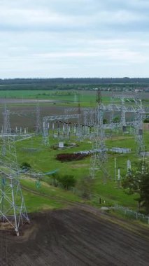 Yüksek elektrik iletim kuleleri bulutlu bir gökyüzünün altında geniş yeşil bir alana yerleştirilmiş ve enerji taşımacılığı ve dağıtımı için gerekli altyapıyı göstermektedir.