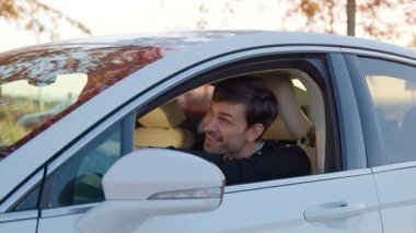 Erkek müşteri test sürüşünden önce arabanın içini keşfediyor, sürücü koltuğunda rahatça oturuyor, modern özellikleri vurguluyor ve atmosferi davet ediyor.