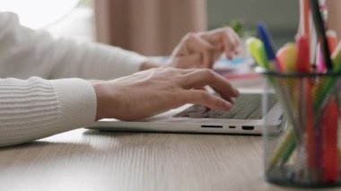 Bilgisayar klavyesine yazı yazan bir çocuğun yan görüntüsü. Ofis masası ve ofisteki dizüstü bilgisayarda çalışan ve internette sörf yapan bir adamın elleri.