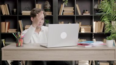 Erkek öğrenci çevrimiçi bilgisayar derslerine uzaktan katılıyor. Genç adam görüşünü öğretmenlerine ifade etmek için elini kaldırır. Çevrimiçi uzaklık öğrenimi