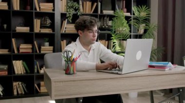 Gözlüklü genç tebeşir gibi çocuk önemli bir proje üzerinde çalışan bir bilgisayarda daktilo yazıyor. Öğrenci internette bir ofisteki dizüstü bilgisayarda bilgi arıyor.