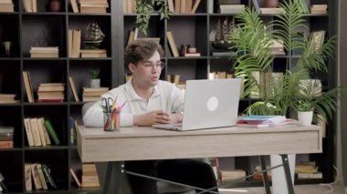 Ofis masasında bilgisayarın önünde oturmuş üniversite projesini tartışan ve sunan genç bir öğrenci. Kameraya konuşan gözlüklü çocuk uzaktan canlı yayında