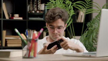 Konsantre ve odaklanmış genç çocuk okul arasında boş zamanlarında modern bir telefonla online oyunlar oynuyor. Çocuk en son aletleri eğlence için kullanıyor.