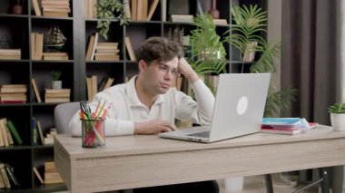 Modern bir ofiste gözlüklü bir çocuk bilgisayarda dikkatle okur, hoşnutsuz ve şaşkın. Genç öğrenci üniversiteye hazırlanıyor ve bir proje üzerinde çalışıyor.