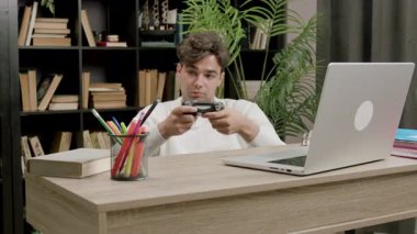 Öğrenci çocuk, teneffüsler arasında üniversitede bankta oturup playstation oynuyor. Genç çocuk online oyunlar için uzaktan kumandayı elinde tutuyor ve boş zamanlarında yeniden yaratıyor.