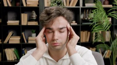 Yorgun esmer öğrenci parmaklarıyla şakaklarına masaj yapıyor. Baş ağrısı çekiyor. Çok fazla öğrenme ve çalışmadan yorgun düşüyor. Kendini adamış öğrenciler ve sürekli öğrenme kavramı