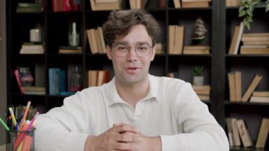 Gözlüklü, kendinden emin genç adam elleriyle kameraya işaret ediyor. Çocuk, projesini uluslararası bir forumda dizüstü bilgisayarın önünde tartışıyor ve sunuyor.