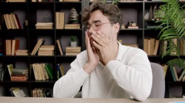 Yorgun genç adam esner ve elini ağzına tutar. Çocuk gözlüklerini çıkarır, gözlerini, ellerini ve boynunu uzatır. Öğrenim dönemi, dersler, sınavlar öğrenciler için çok zahmetli..