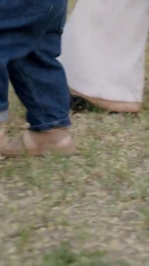 Bebek çimen ve yapraklarla meşgul, canlı bir açık havada dokuları ve renkleri keşfediyor, merakın ve duyusal keşfin özünü yakalıyor.