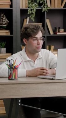 Ofis masasında bilgisayarın önünde oturmuş üniversite projesini tartışan ve sunan genç bir öğrenci. Kameraya konuşan gözlüklü çocuk uzaktan canlı yayında