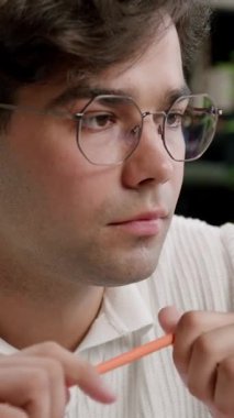 Masada düşünceli ve gülümseyen bir öğrenci, online derslere katılıyor. Genç adam, aklına bir fikir geldiğini ve not defterine not aldığını göstererek başını sallar. Modern bir kütüphanede öğrenci