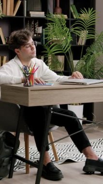 Gözlüklü yorgun çocuk dizüstü bilgisayarı kapatıyor ve acıdan gözlerine ve şakaklarına masaj yapıyor. Güç kazanmak için çalışmayı bırak. Öğrenim için meraklı öğrenci kavramı