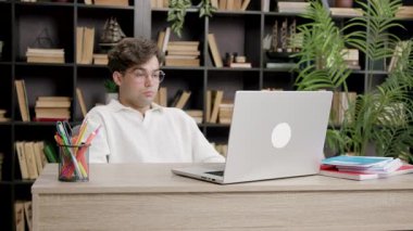 Disappointed student seeing grades from exams at college. Young boy in front of computer nervous and sad participating in online lessons with college colleagues