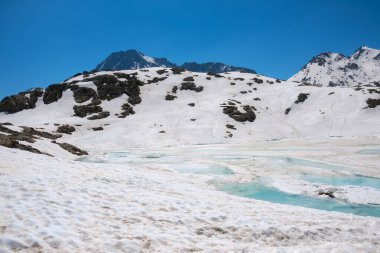 İtalya, Vermiglio yakınlarında karla kaplı güzel bir manzara yakaladık. Beyaz kar ve mavi suyun çarpıcı kontrastı, arka plandaki görkemli dağları aydınlatarak, berrak gökyüzünü yansıtır..