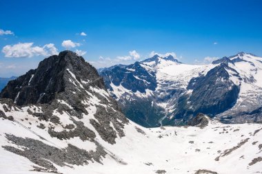 İtalya, Vermiglio 'daki karla kaplı dağların çarpıcı manzarası, parlak mavi bir gökyüzü altında dramatik bir arazi ortaya çıkarıyor. Görkemli zirveler nefes kesici bir doğal manzara yaratır..