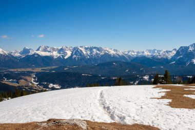 Arka planda büyüleyici dağlar yükselirken kar zemini kaplıyor Garmisch-Partenkirchen 'in kış güzelliğini gözler önüne seriyor..