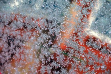 Delicate frost patterns adorn a window in Vastanvik, Dalarna, creating a stunning view into the snowy landscape outside. The vibrant colors from within contrast with the icy designs of winter. clipart