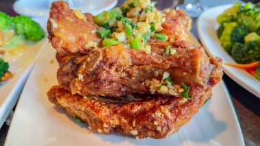 Çin usulü domuz pirzolası diğer Çin yemeklerinin yanında bir restoranda bir tabakta.. 