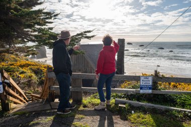 20 Nisan 2024, Bandon, Oregon, ABD. Old Rustic Cabin Motel 'e bakan turist çifti.