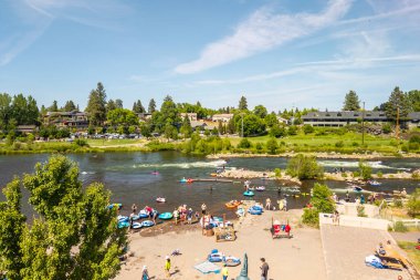 15 Haziran 2025, Bend, Oregon, ABD. İnsanlar, Deschutes Nehri 'nin Eski Değirmen Bölgesi' nden akan bu tembel öğleden sonranın tadını çıkarıyorlar. Drone görünümü.
