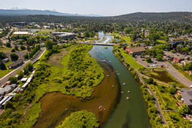 15 Haziran 2025, Bend, Oregon, ABD. İnsanlar, Deschutes Nehri 'nin Eski Değirmen Bölgesi' nden akan bu tembel öğleden sonranın tadını çıkarıyorlar. Drone görünümü.