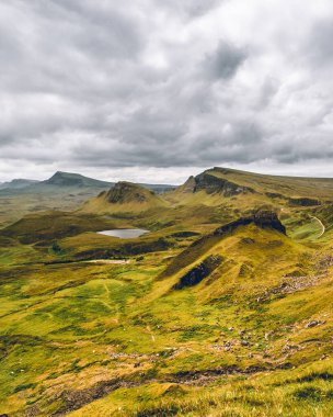 Quiraing, İskoçya 'da büyüleyici bir bakış açısıyla geniş bir manzara gözler önüne seriliyor. Sarp kayalıklar, yeşil yamaçlar ve geniş vadiler dramatik bir tablo oluşturur. Doğanın yüceliğinin hüküm sürdüğü, duyularını büyülediği ve bir u sunduğu bir yer.